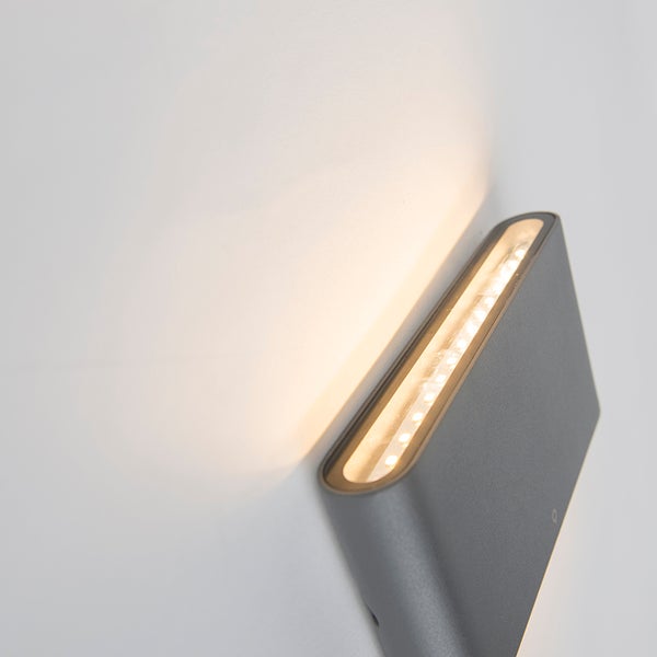 Moderne LED-Wandleuchte in Grau mit warmweißem Lichtaustritt nach oben.