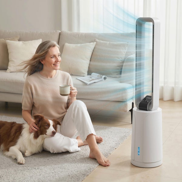 Weißer rotorloser Turmventilator im hellen Wohnzimmer, kühle Luft strömt zu einer Frau und ihrem Hund auf einem Teppich.