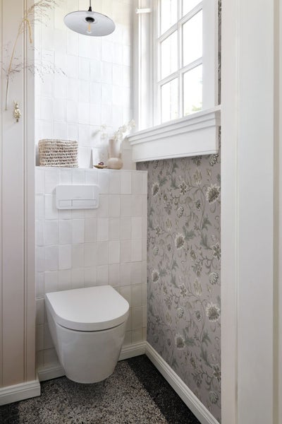 Badezimmer mit Toilette, Waschbecken und floraler Tapete