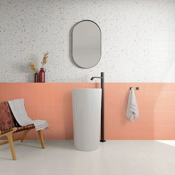 Modernes Badezimmer mit freistehendem Waschbecken, ovalem Spiegel, terrazzoartiger Wandfliese und pfirsichfarbenen Fliesen, minimalistisch gestaltet.