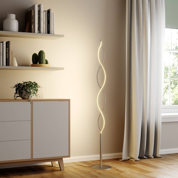 Moderne LED-Stehleuchte mit geschwungenem Wellendesign in einem hellen Wohnzimmer neben einem Sideboard.