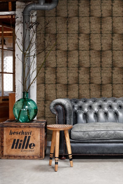 Wohnraum mit gemusterter Tapete, Sofa und Holzhocker