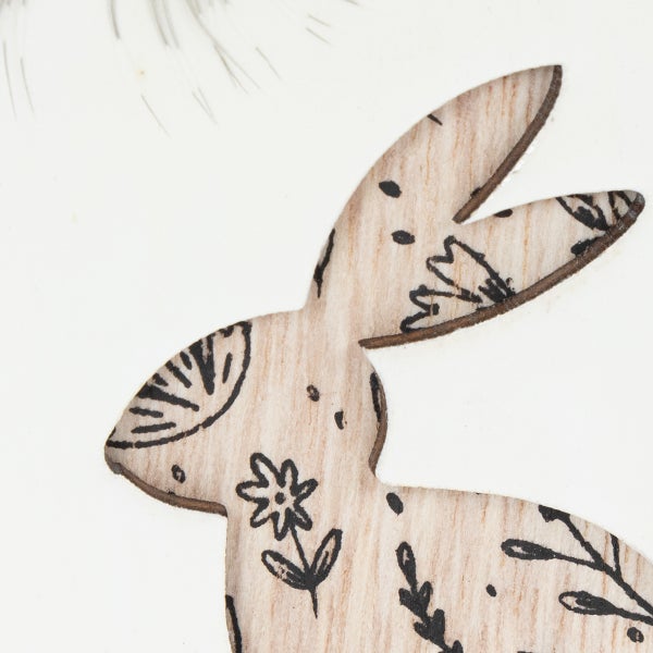 Detail einer Holzfigur in Form eines Hasen mit schwarzen floralen Mustern