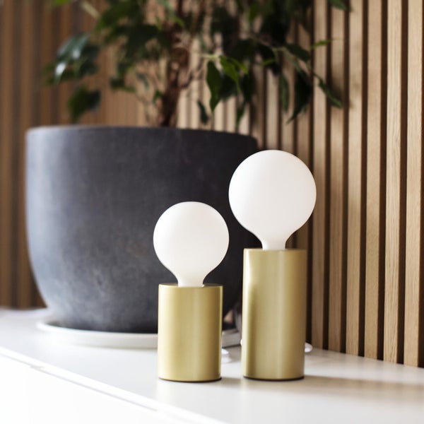 Zwei Tischleuchten mit kugelförmigen Lampenschirmen und zylindrischen Sockeln stehen auf einem Tisch