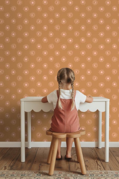 Mädchen am Tisch vor einer Wand mit Sonnen- und Mondmuster