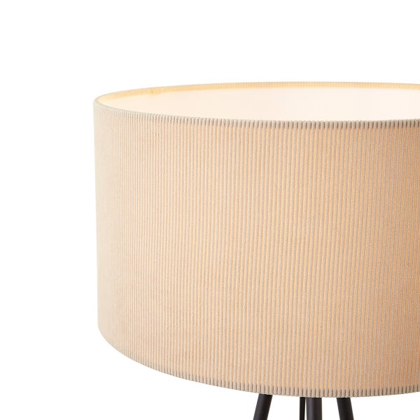 Detailansicht eines zylindrischen Lampenschirms aus beigem Textil mit Rippenstruktur auf einem schwarzen Dreibeinstativ.