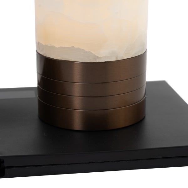 Detailaufnahme einer Tischleuchte mit Alabaster-Zylinder, bronze-farbenem Metallelement mit Rillen und schwarzem Sockel.