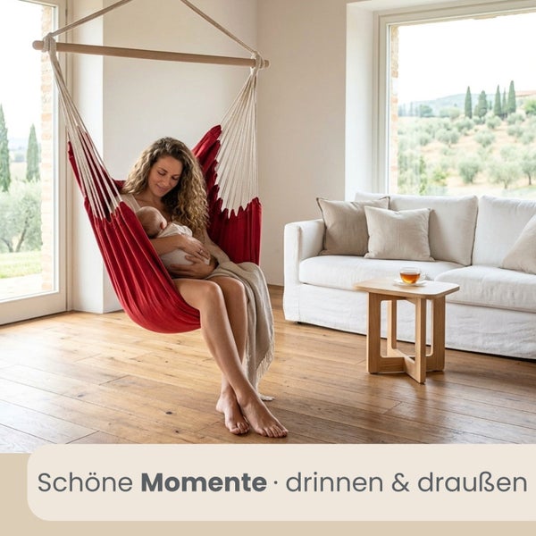 Roter Hängesessel in einem hellen Wohnzimmer mit Frau und Baby, Holzboden und Sofa vor einem großen Fenster.