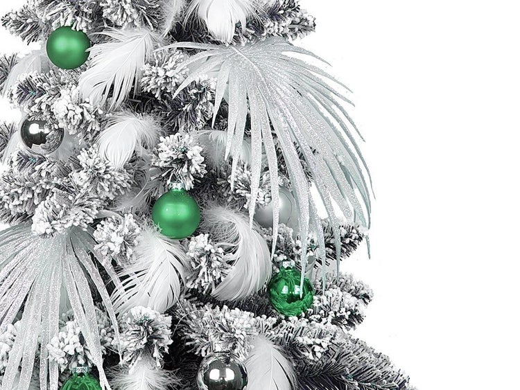 Künstlicher Weihnachtsbaum mit Schnee, Federn und Weihnachtskugeln dekoriert.
