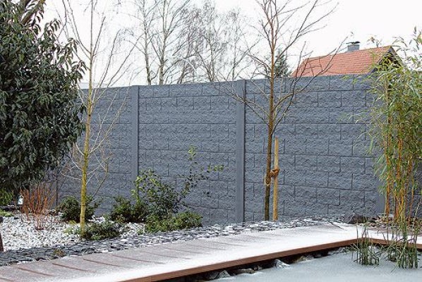 Garten mit grauer Betonmauer als Sichtschutz