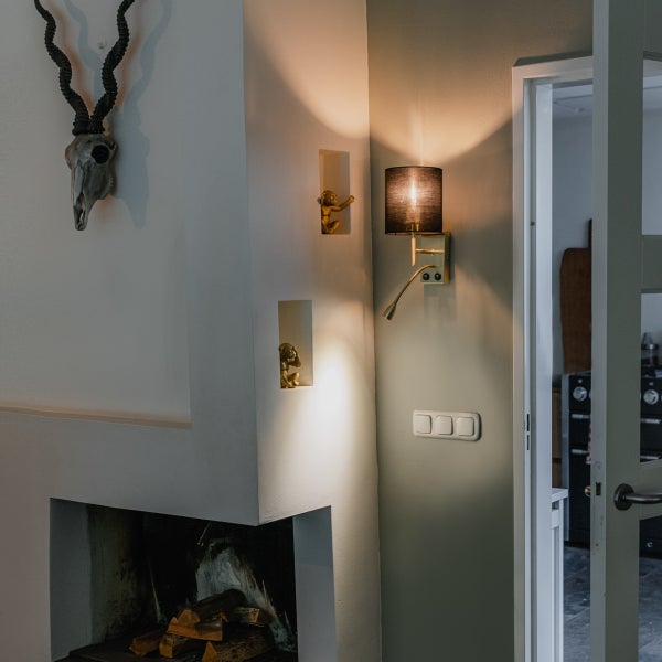 Wohnzimmer mit Kamin, Geweih, Wandleuchte und goldenen Affenfiguren