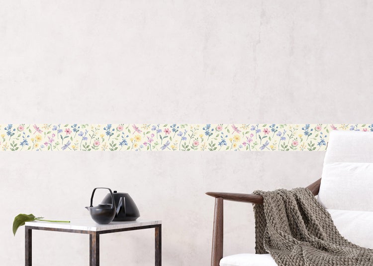 Helles Wohnzimmer mit Vliestapete im botanischen Design, hellem Sofa, Holztischen und Fischgrätparkett.