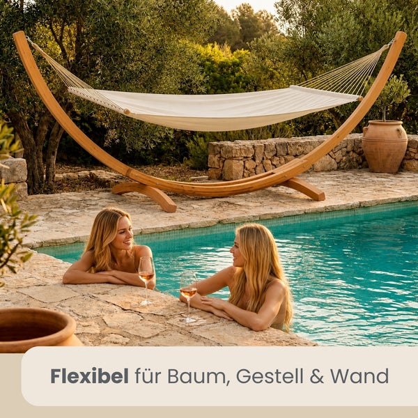 Hängematte mit bogenförmigem Holzgestell auf einer Steinterrasse neben einem Pool, umgeben von einem Garten, flexibel für Baum, Gestell und Wand.