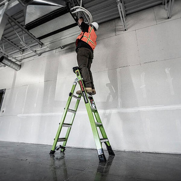 Handwerker steht auf einer Little Giant Kombinationsleiter in einer Industriehalle und arbeitet an der Deckenkonstruktion.