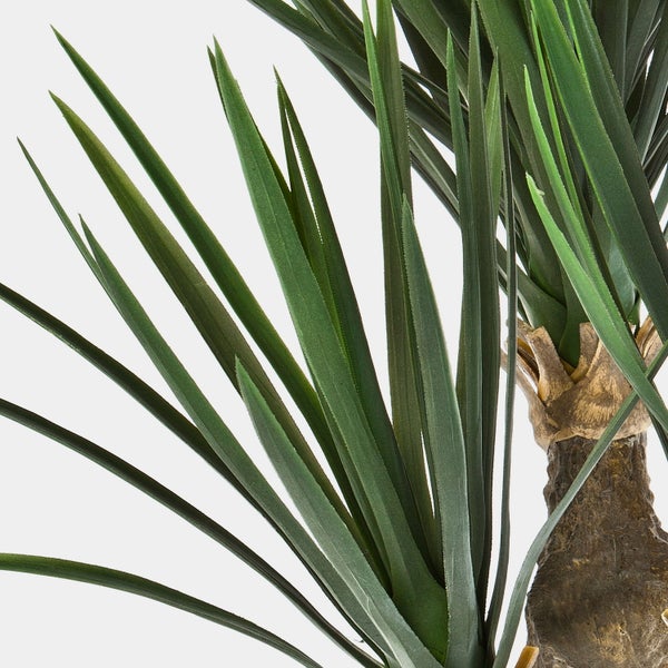 Künstliche Yucca Pflanze Detailansicht mit langen, spitzen Blättern und strukturiertem Stamm.