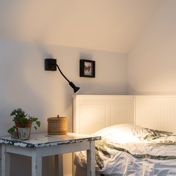 Schlafzimmer mit Bett, Nachttisch und Wandleuchte