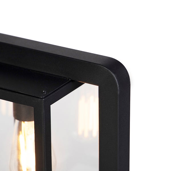 Detailansicht einer schwarzen Außenwandleuchte aus Metall und Glas mit sichtbarem Filament-Leuchtmittel.