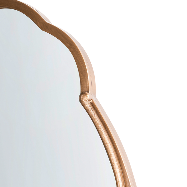 Detail eines Wandspiegels mit geschwungenem Metallrahmen in Messing-Optik.