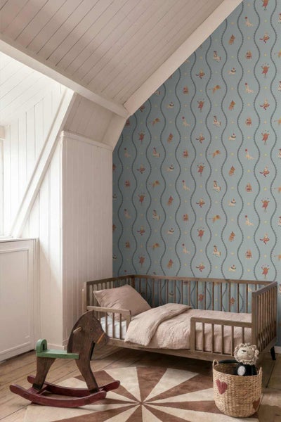 Kindertapete mit Zirkusmotiven in einem Zimmer mit Holzbett, Schaukelpferd und Dachschräge.