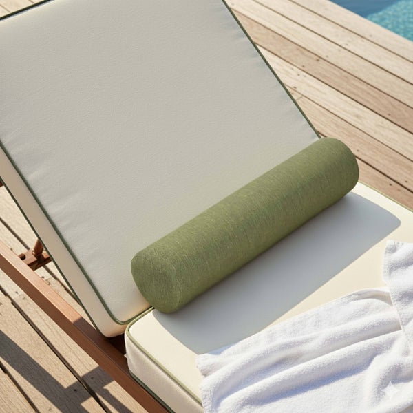 Grüne Nackenrolle auf einer cremefarbenen Gartenliegen-Auflage auf einer Holzterrasse am Pool.