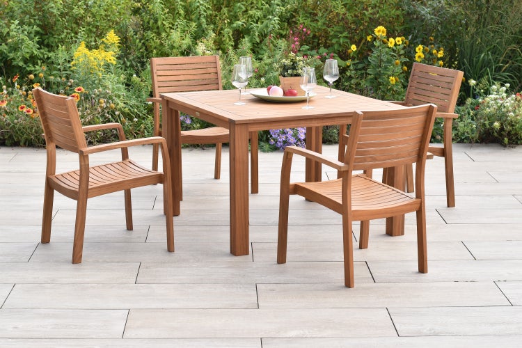 Quadratischer Gartentisch mit vier Armlehnstühlen auf einer Terrasse.