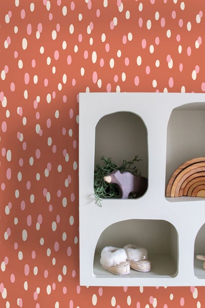 Wand mit Tupfentapete, Regal mit Holzspielzeug und Babyschuhen