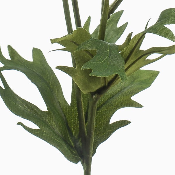 Detailaufnahme der grünen Blätter einer Kunstpflanze mit gezackten Rändern.