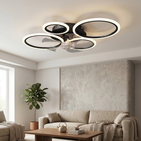 Moderner Deckenventilator mit vier LED-Ringen und transparenten Flügeln in einem hellen Wohnzimmer mit beigem Sofa und Holztisch.