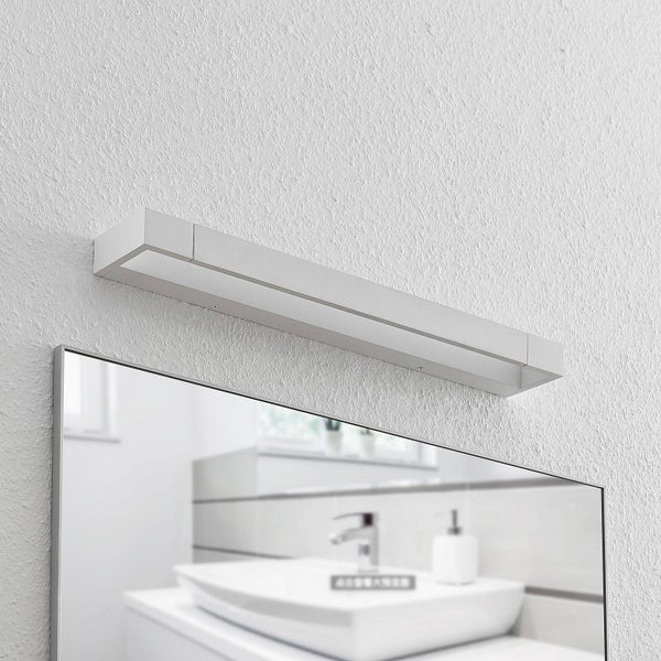 Moderne, lineare LED-Spiegelleuchte über einem Badezimmerspiegel in einem hellen Badezimmer im minimalistischen Stil.