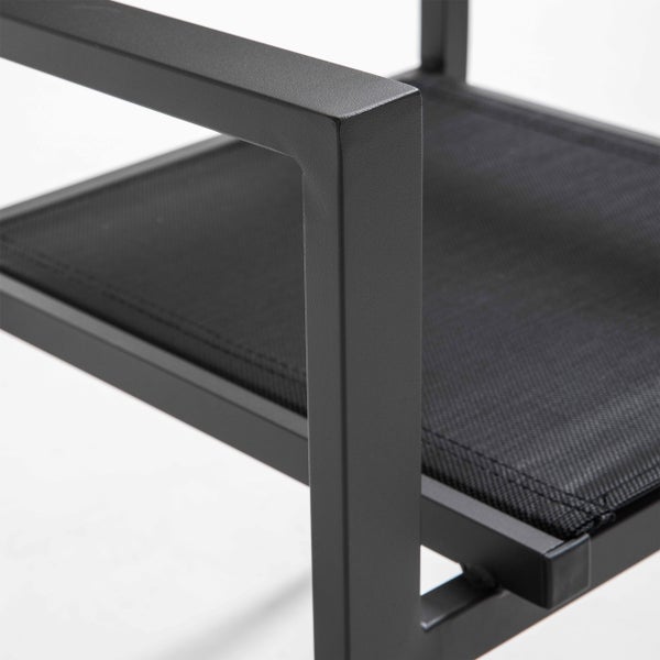 Detailaufnahme eines schwarzen Gartenstuhls mit Armlehne aus Metall und Sitzfläche aus Mesh.