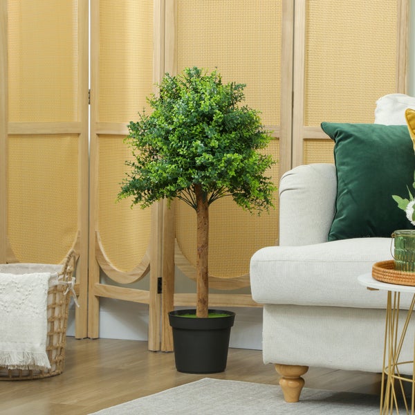 Künstlicher Eukalyptusbaum im Topf neben einem Sofa und einem Raumteiler