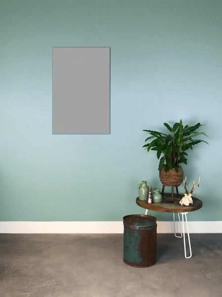 Minimalistischer Raum mit blaugrüner Wand und grauer rechteckiger Fläche. Ein runder Holztisch mit weißen Haarnadelbeinen steht davor.