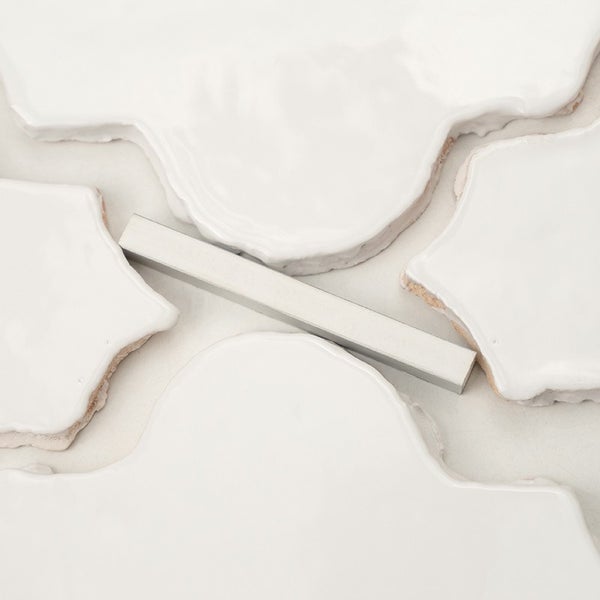 Weiße Wandfliesen in organischer Form mit glänzender Oberfläche und Metallprofil.