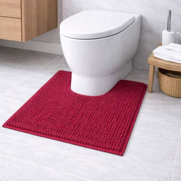 Rote WC-Vorlage mit Noppenstruktur und Ausschnitt vor einer weißen Toilette in einem hellen Badezimmer mit grauen Bodenfliesen.