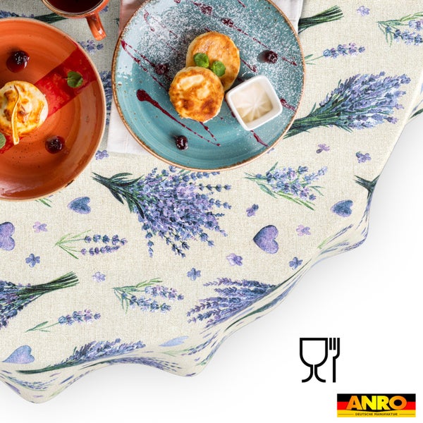 Wachstuch-Tischdecke mit Lavendel- und Herzmotiv, gedeckt mit Frühstückstellern. Lebensmittelecht. ANRO Logo.