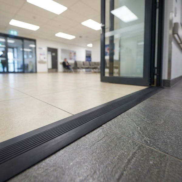 Eine Türschwelle als Bodenprofil installiert in einem Durchgangsbereich eines öffentlichen Gebäudes für einen barrierefreien Übergang.