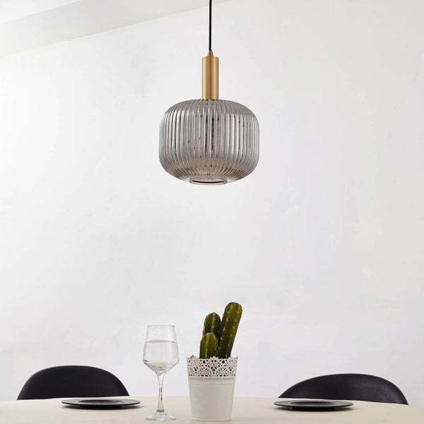 Moderne Pendelleuchte mit geriffeltem Glasschirm und Messing-Halterung über einem gedeckten Esstisch.