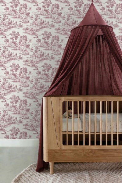 Toile-de-Jouy-Tapete mit ländlichem Landschaftsmuster in einem Kinderzimmer mit Holzbabybett und Stoffbaldachin.