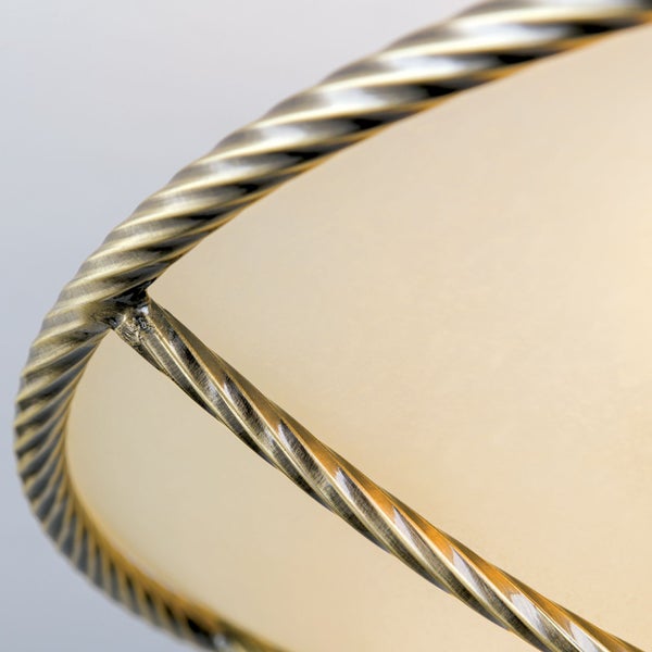 Detailansicht eines Lampenschirms mit gedrehtem Metallrahmen in antiker Optik und beigefarbenem Textilbezug.