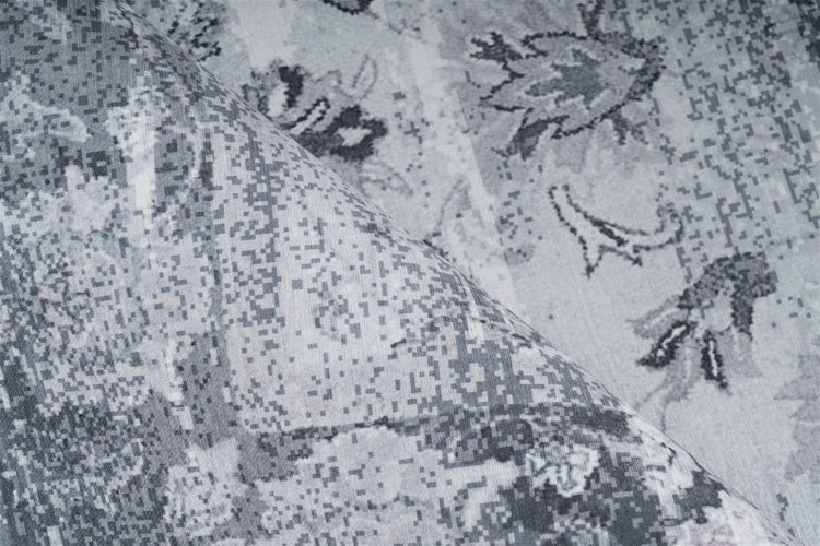 Nahaufnahme eines Teppichs mit verpixeltem Vintage-Orientmuster in Grautönen.