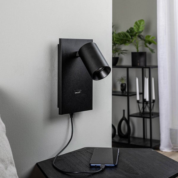Schwarze Wandleuchte mit USB-Anschluss und Handy auf einem Nachttisch