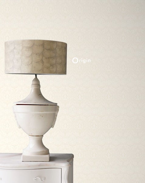 Dekorative Tischlampe auf einem weißen Nachttisch vor einer gemusterten Tapete
