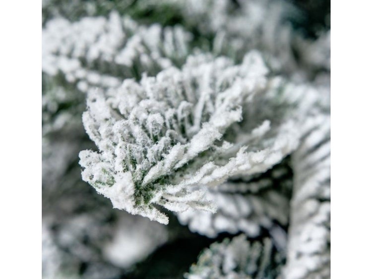 Detailansicht eines künstlichen Weihnachtsbaumzweigs mit künstlicher Schneeoptik.