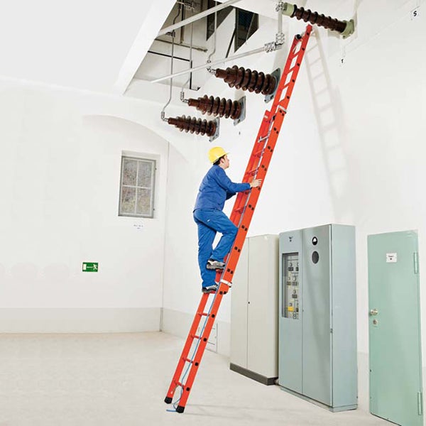 Eine Person mit Schutzhelm steigt eine Leiter in einem Innenraum hoch, um an elektrischen Anlagen zu arbeiten.
