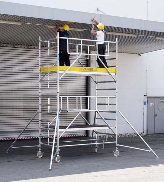 Fahrgerüst mit zwei Personen bei Arbeiten an einem Gebäude.