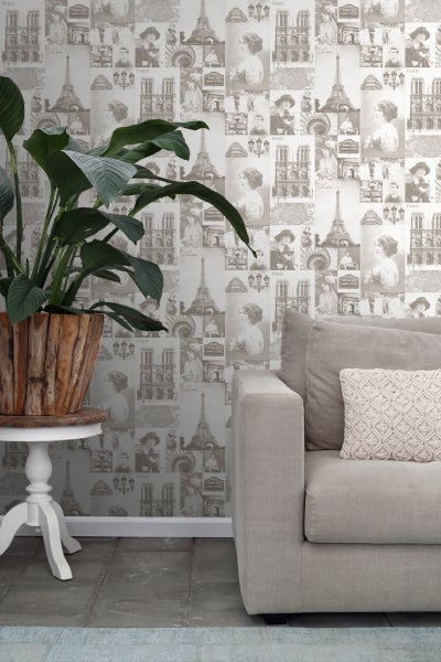 Wohnraum mit Paris-Motivtapete, Pflanze im Holztopf auf Beistelltisch und Sofa mit Kissen