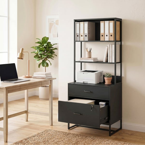 Schwarzer Aktenschrank mit Regalaufsatz in einem hellen Homeoffice neben einem Schreibtisch aus Holz.