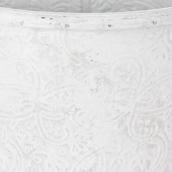 Nahaufnahme eines weißen Pflanztopfes mit geprägtem Blumenmuster und antiker Oberfläche.