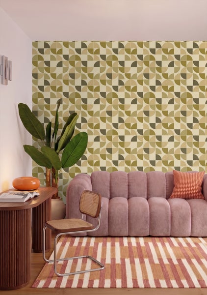 Tapete mit geometrischem Retromuster in einem Wohnzimmer mit rosa Sofa, Holzschreibtisch und gestreiftem Teppich.