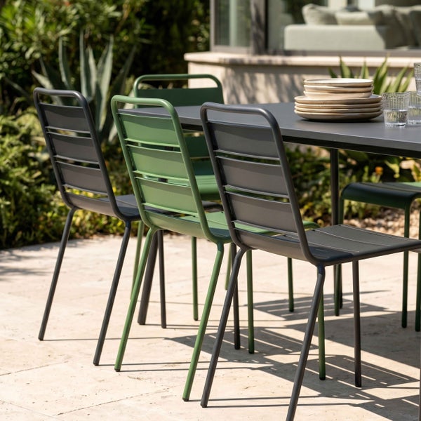 Modernes Gartenmöbel-Set mit Metallstühlen und rechteckigem Tisch auf einer Steinterrasse, hell und geordnet gestaltet.
